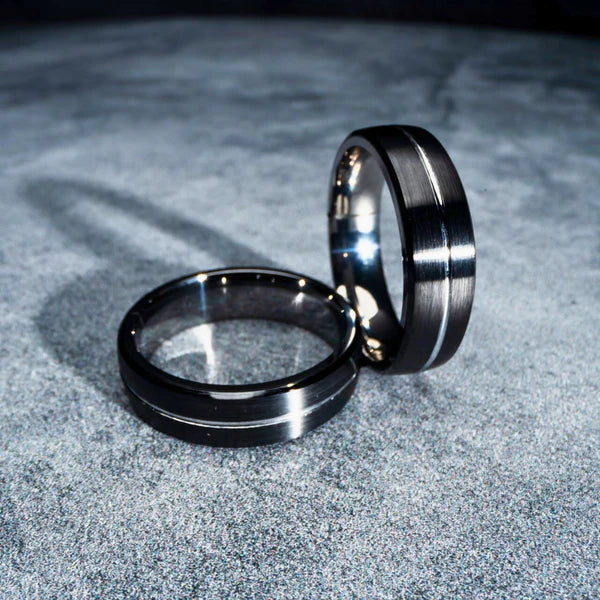 This image displays two sleek, modern NFC rings, likely crafted from a durable metal such as titanium or tungsten. The ring on the left features a smooth, glossy finish with a classic, elegant appearance.