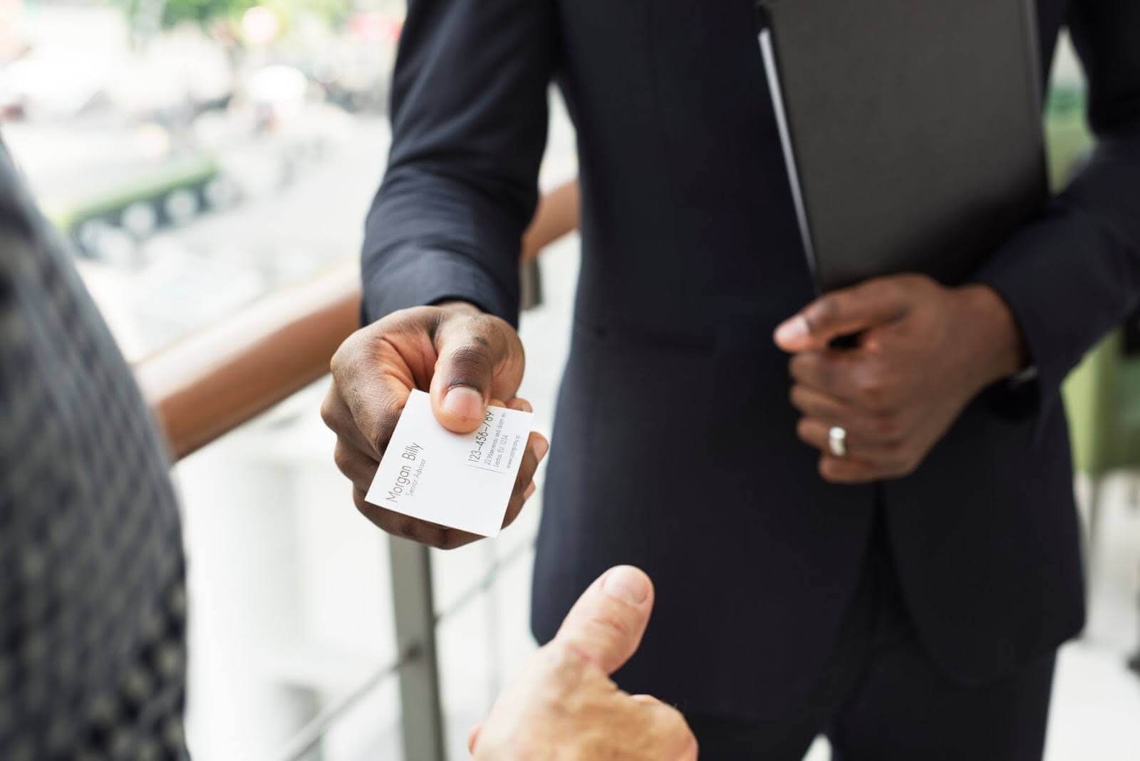a professional sharing his paper business card with a client 