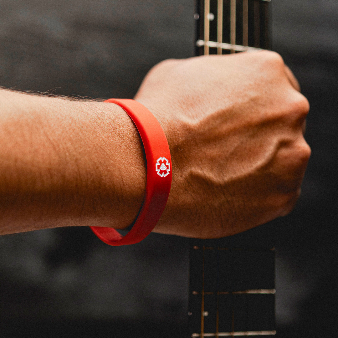 Red Medical Band on a hand holding a guitar