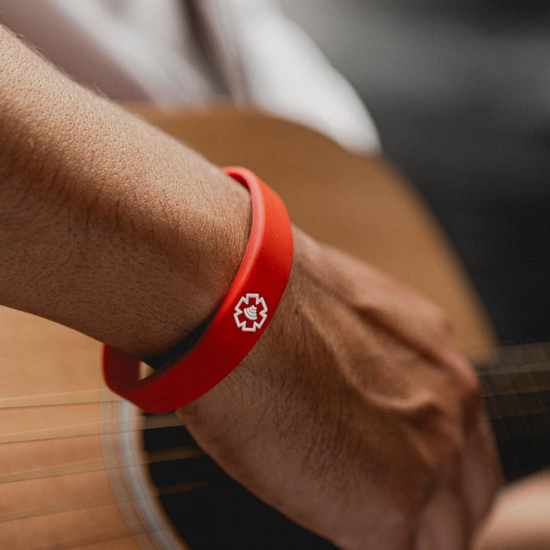 Red NFC Medical Band on a hand playing guitar